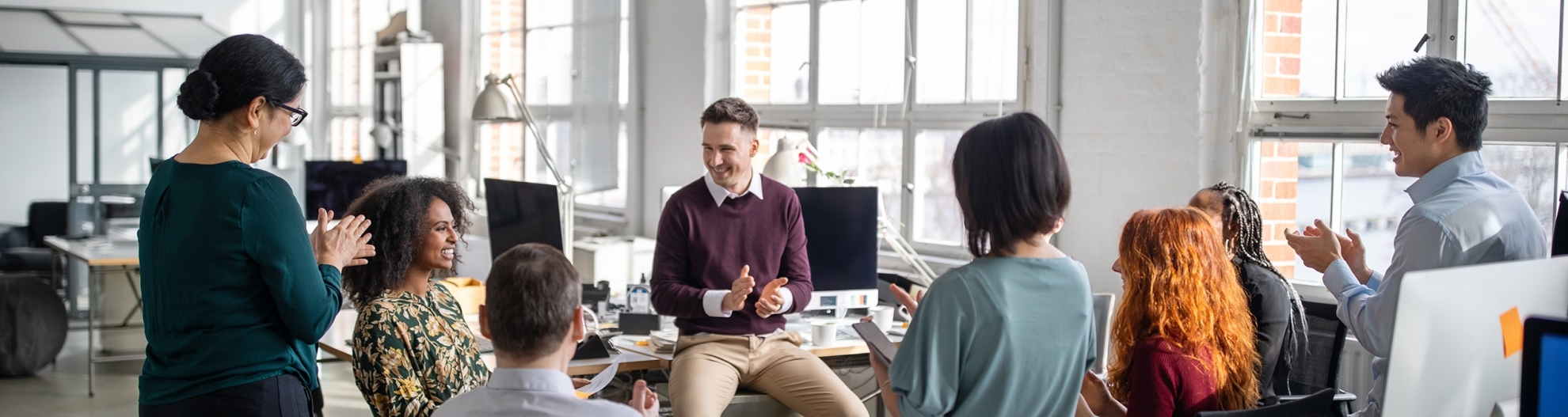 Business team clapping for a female colleague in meeting_